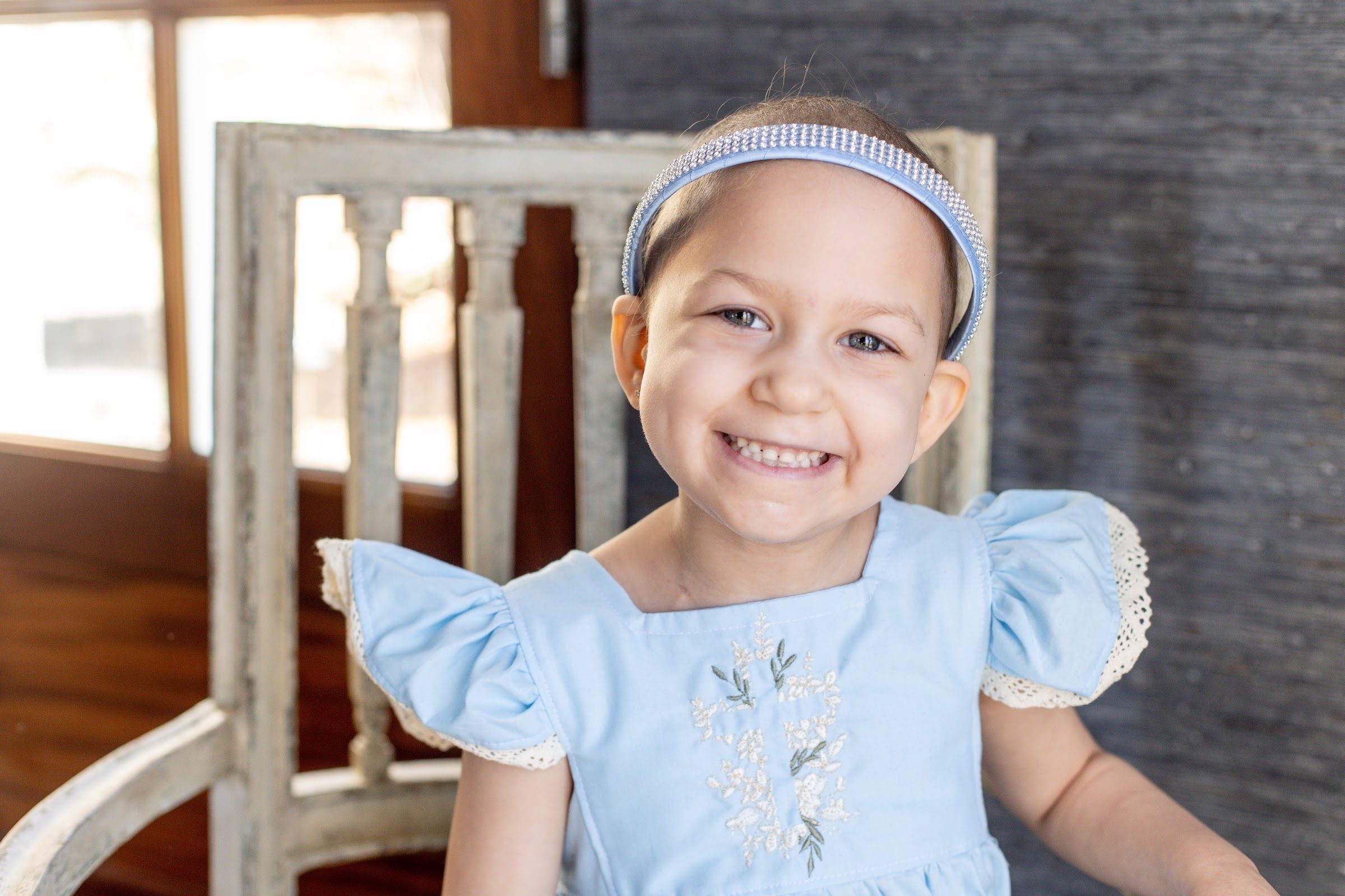 Greenleigh, a Rally Kid, smiling in a light blue dress and headband